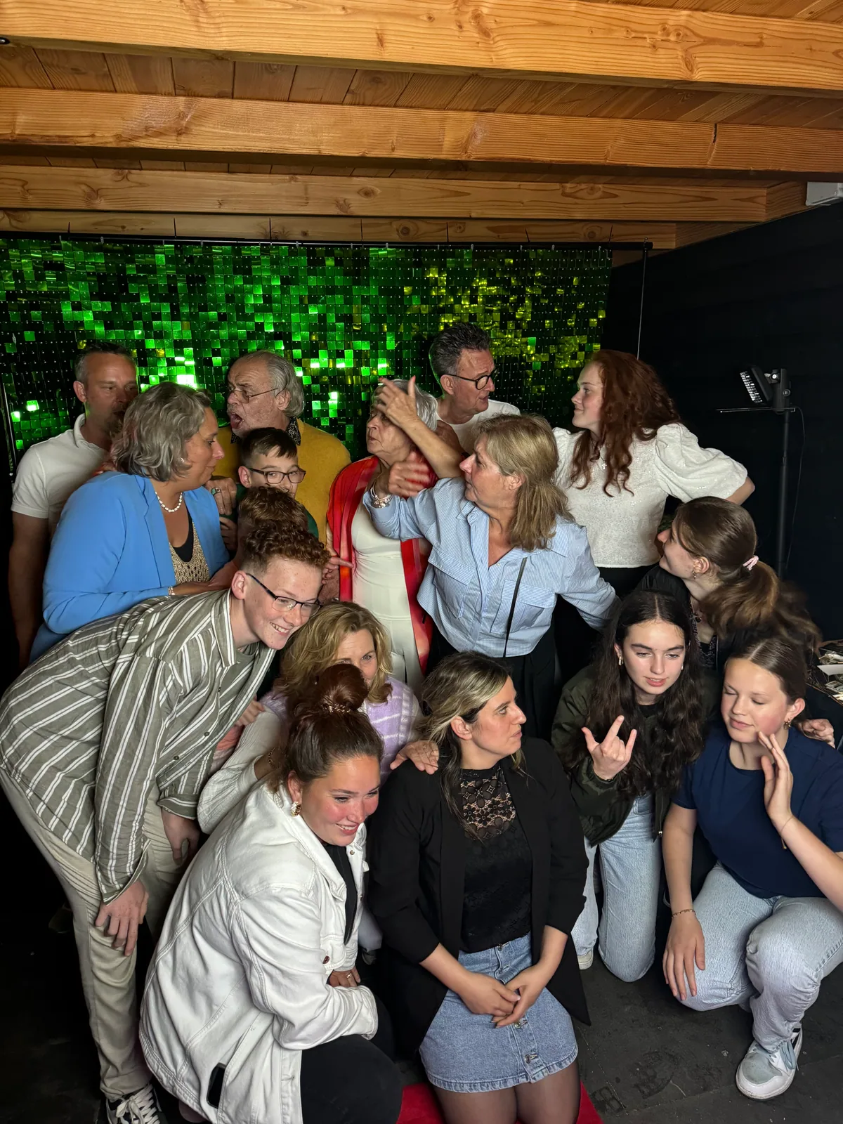 Grote groep gasten poseert spontaan voor een groene feestachtergrond.