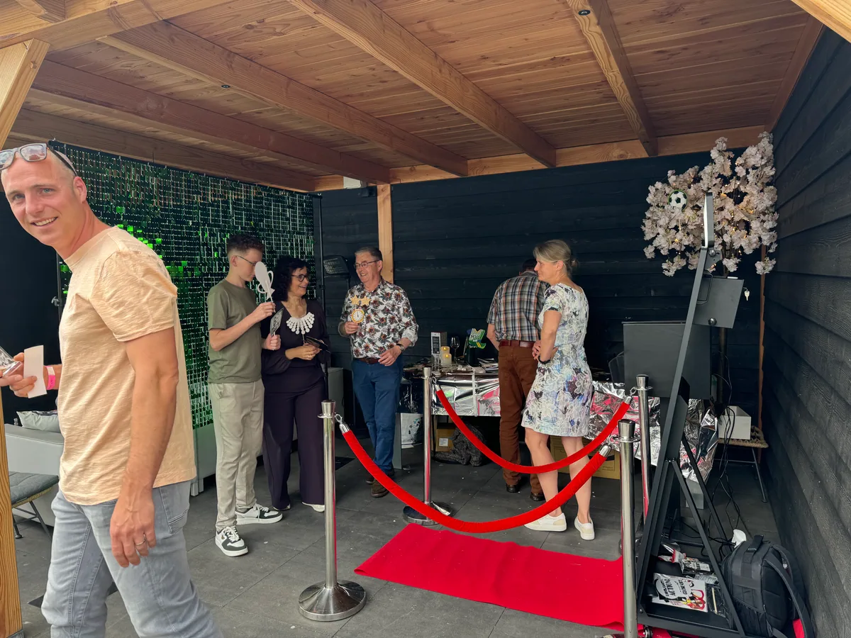 Gasten verzamelen zich bij een Mirror Booth-opstelling met rode loper tijdens een evenement.